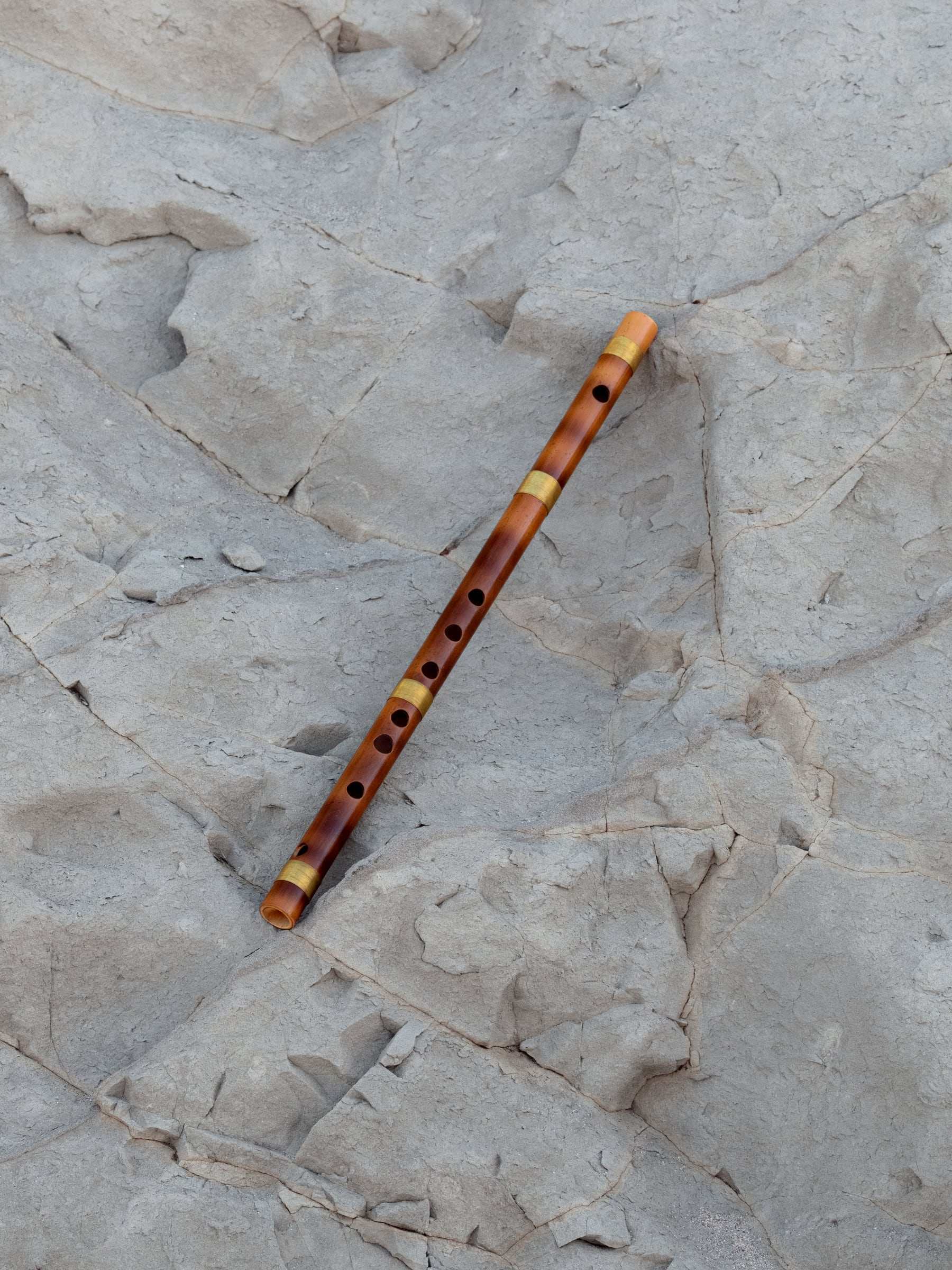 A bamboo bansuri on weathered pale rock