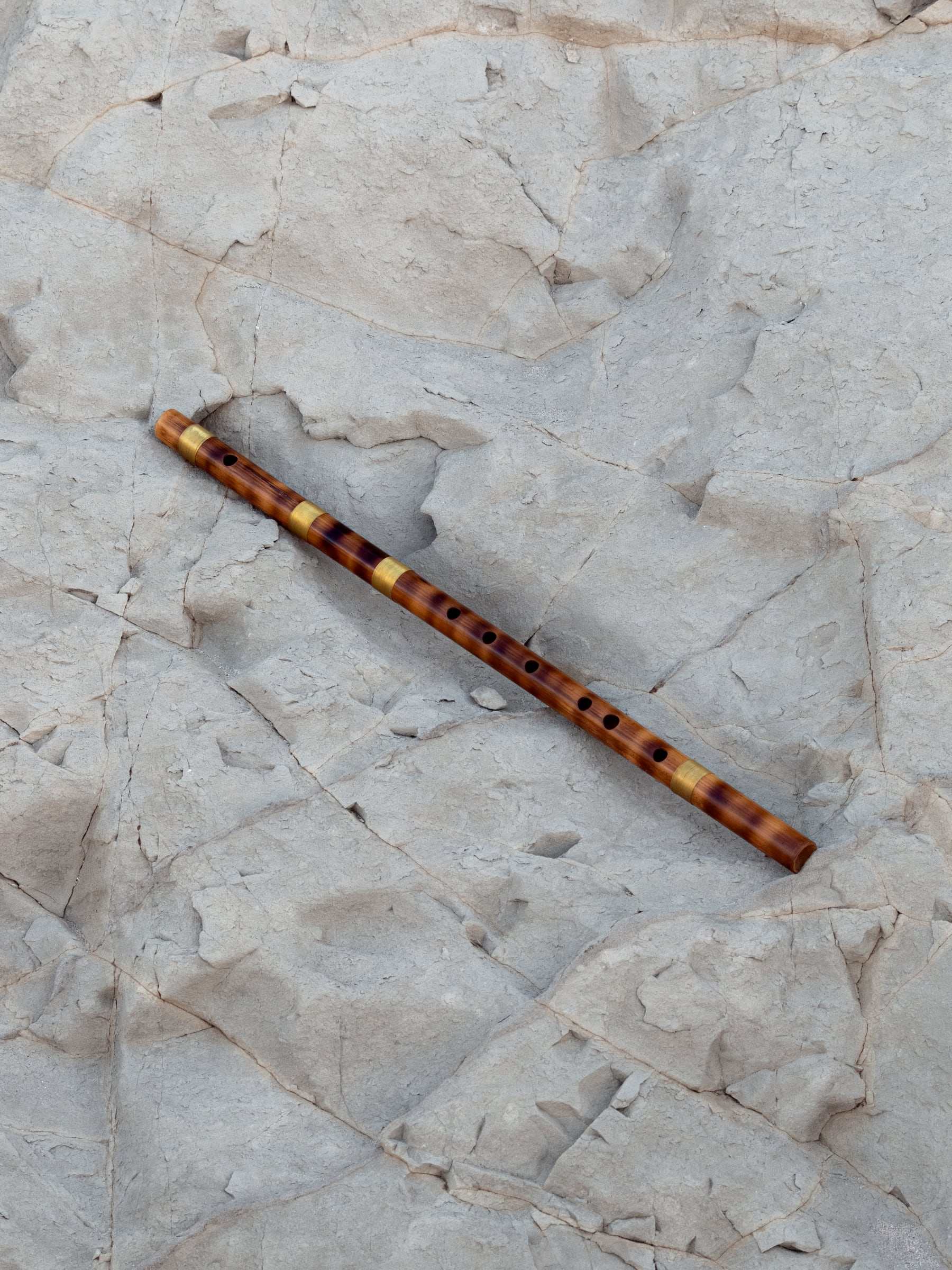 A bamboo bansuri on weathered pale rock