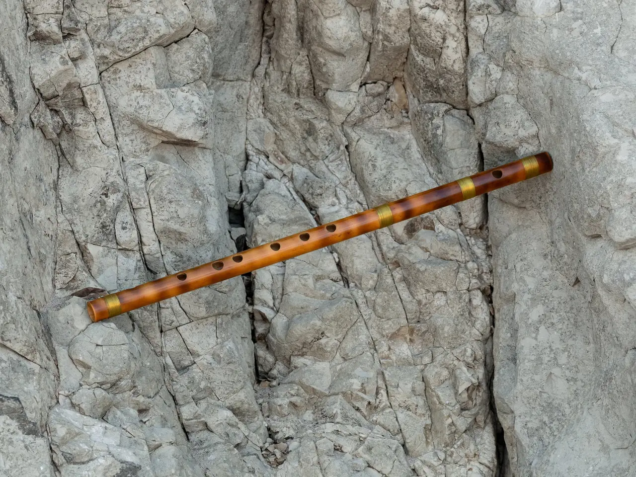 A bamboo bansuri resting against a crevice in pale rock