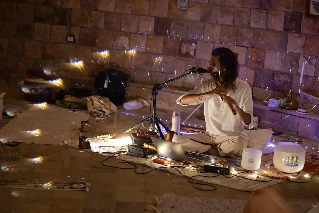 Federico plays the bansuri seated among crystal singing bowls and small lights