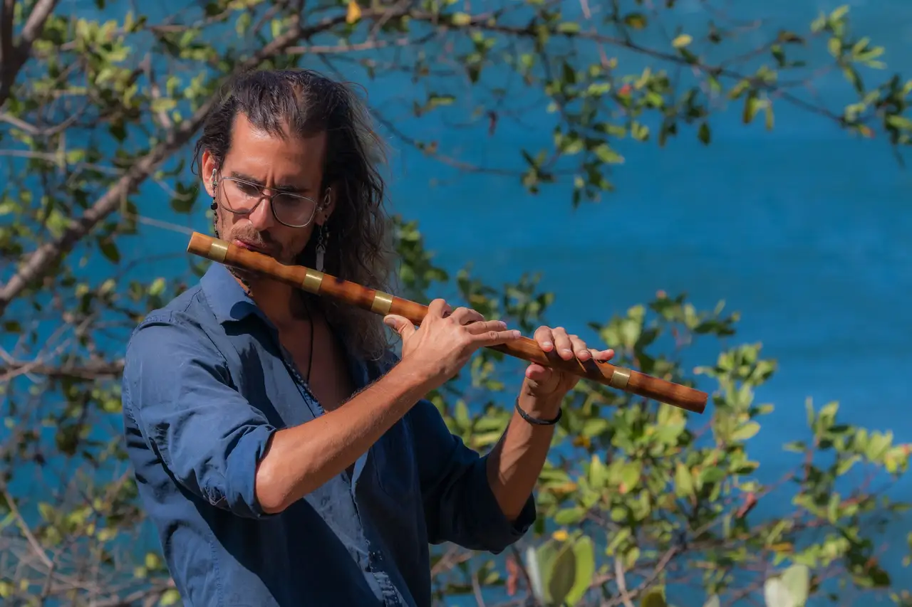 Federico plays the bansuri among trees above the sea