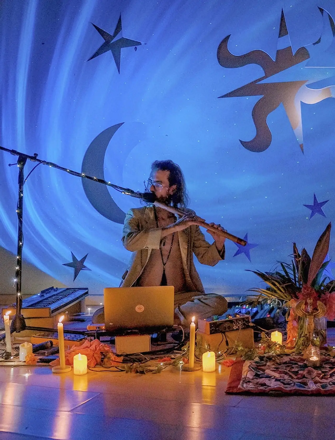 Federico plays the bansuri on a stage painted deep blue with a crescent moon and stars