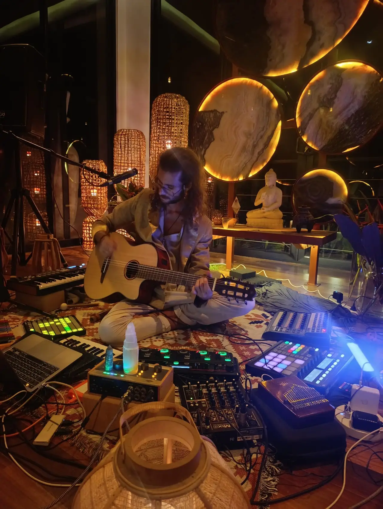 Federico with a guitar in a studio full of synthesizers, gongs and warm lights